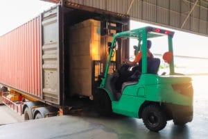 Empilhadeira transporta excesso de carga para dentro de um caminhão.