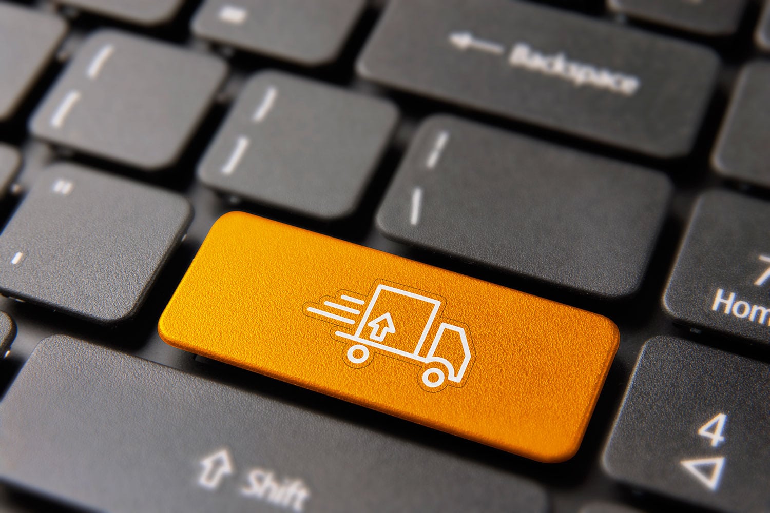 Botão com símbolo de caminhão em teclado de notebook, simbolizando o marketplace de frente para transporte de cargas.