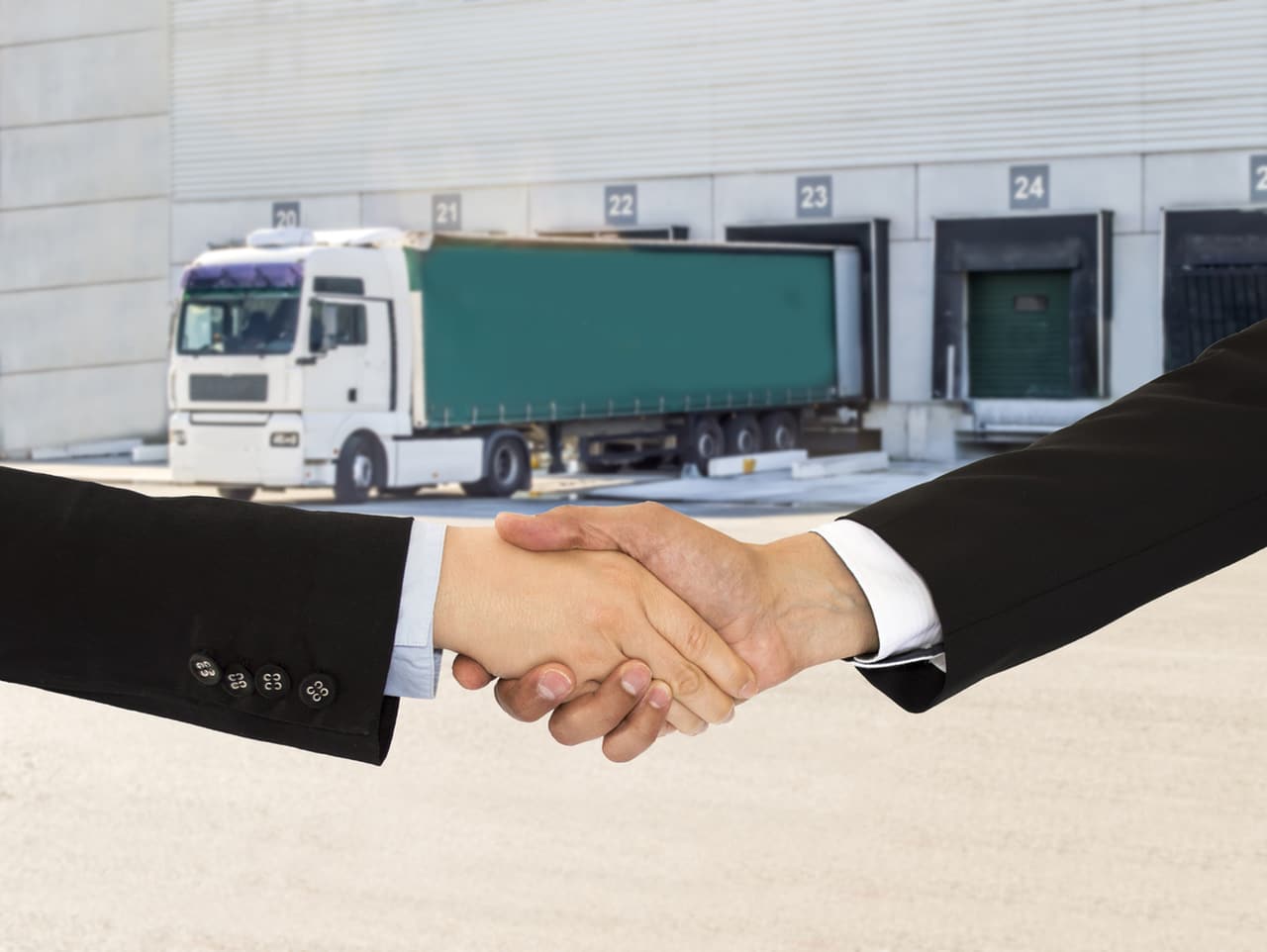 Cliente e vendedor apertam as mãos em frente a um caminhão, simbolizando o Programa de Parceria da Cargo X.