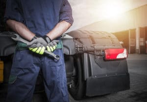 Mecânico com ferramentas em frente a um caminhão ilustra a gestão de manutenção em transportadoras.